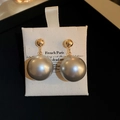 Detailed shot of large grey pearl drop earrings with gold ball studs on a French display card - Silver Needle - Gray (Real Gold Plated) / Gray