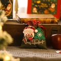 Green burlap Christmas gift bag with a 3D snowman and festive tree on a wooden box - Snowman Green Drawstring Bag