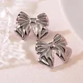 Close-up of silver-tone polished titanium steel bow earrings with 3D pleated texture - Bow