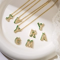 Collana con lettera in oro e smalto verde con cristalli su un piatto bianco - Lettera A / Verde