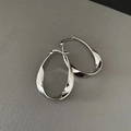 Macro shot of silver twisted hoop earrings with a polished metallic finish on leather - Twisted Hoop / Silver