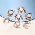 Detailed view of gold moon charms with opal hearts and rhinestones on a mirror surface - Style 8-Moon Hugging Heart Gold