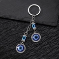 Macro detail of vintage tribal Hamsa hand keychain with blue evil eye on black stone - Double Round Eye