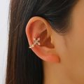 Macro view of gold-plated cross ear cuff with white zircons on a model's ear - Cross Style (12388) / Gold
