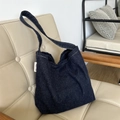 Détail d'un sac cabas en denim bleu foncé avec étiquette sur une chaise en cuir blanc - Bleu marine