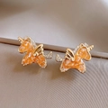 Nahaufnahme von goldenen Einhorn-Ohrsteckern mit orangen Edelsteinen auf Seide - Silberstecker Gold Kaffee