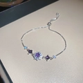 Close-up of adjustable silver bracelet featuring purple gemstones and sparkling zircon flowers - Purple Flower / Silver