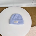 Close-up of light blue knit beanie showing thick wool texture and BAKE fabric label - Light Blue
