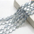 Close-up of faceted blue-grey diamond-shaped crystal glass beads on a white pedestal - Light Blue Grey