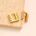 Dettaglio di orecchini geometrici quadrati dorati con zirconi su pietra beige - Stile Zircone Quadrato Dorato (CK50-GD)