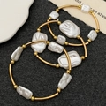 Set of three golden metal bracelets with white baroque pearls on a dark textured background - Gold Baroque Pearl Metal Tube Bracelet (Set of 3) (2953)