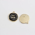 Detail view of round gold cherry charms with black enamel and textured back with engraving - Black Cherry
