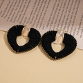 Close-up of black yarn-wrapped hollow heart hoop earrings on vintage newspaper background - Black