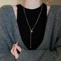 Détail d'un collier en Y plaqué or avec un pendentif cube en strass étincelant sur un modèle - Pendentif Carré Sucre Doré Chaîne Serpent