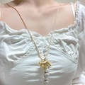 Dettaglio della collana con ciondolo a forma di pony dorato su camicia bianca - Pony d'Oro (2029)