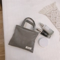 Détail du mini sac cabas en velours côtelé gris avec étiquette sur fond de tissu gaufré - gris foncé