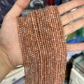 Faceted natural orange stone beads strand for jewelry making shown in hand detail - Grade B Sunstone 3mm