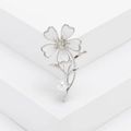 Elegante broche floral con pétalos blancos, cristal central y perla en tallo plateado - Plateado