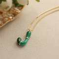 Dettaglio di una collana d'oro con un ciondolo a lettera J in smalto verde lucido - Lettera J