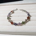 Bracelet trèfle en argent avec zircons colorés en forme de goutte sur un plateau en velours - Or 18K / Platine