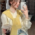 Dettaglio di uno scialle in maglia giallo su camicia beige e jeans per stile casual - Giallo