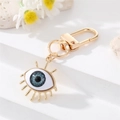 Macro view of evil eye keychain with blue resin eyeball and golden eyelash detail - Eyelashes Grey Eye