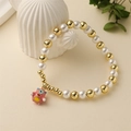 Detail of beaded bracelet with faux pearls, gold copper beads and a pink monster charm - Pink Monster