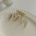 Detail of a wavy gold metal claw clip with pearlescent white resin on a white plate - Pearlescent Mermaid Color