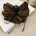 Dettaglio della molletta per capelli leopardata con pizzo e nastri neri su un libro - Stile Fiocco Classico (Pinza-Caffè-Leopardo) / Leopardo Caffè