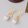 Elegant gold earrings with V-logo and white baroque pearls on a gray background - Gold Hollow V-logo Baroque Pearl