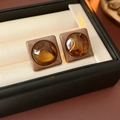 Gros plan de boucles d'oreilles ambre carrées avec gemmes facettées dans un écrin à bijoux - Tige en Argent Café Carré