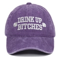 Close-up of "DRINK UP BITCHES" white embroidery on a purple washed cotton baseball cap. - Adjustable / Purple