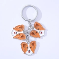 Detail eines Hunde-Schlüsselanhängers mit orange-weißen Emaille-Anhängern aus Metall - Papillon