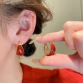 Elegant red enamel gold-plated geometric hoop earrings worn by a model in red sweater - Red Hoop Buckle