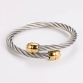 Detail eines gedrehten Kabel-Stahlarmbands mit vergoldeten Enden und silberner Seilstruktur - Silberkabel mit goldenen Enden - 60 mm Innendurchmesser