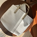 Detailed close-up of woven canvas texture and brown leather handle with metal rivets - Cream