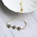 Detail eines verstellbaren Gold-Bolo-Armbands mit blauen Zirkon-Blumen und funkelnden Steinen - Tintenblau