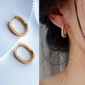Detail view of gold U-shaped hoop earrings with cream enamel on a model and background - Milk Tea
