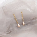 Eleganti orecchini a catena dorata con perle a goccia su sfondo di tulle grigio - Perla Rosa Ago d'Argento