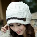 Close-up of cream knit winter hat featuring cable texture and brown leather strap detail - White