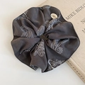 Detailed view of dark grey paisley fabric scrunchie with decorative brand button - Flower Cluster / Gray
