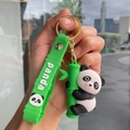 Close-up of a cute panda plush keychain with a green bamboo and a silicone wrist strap - Bamboo Strap - Holding Bamboo Left