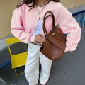 Minimalist brown leather handbag with strap buckle and dual handles in outdoor street setting - S / Pink