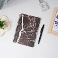 Taccuino a spirale A5 con copertina marmorizzata caffè scuro e penna nera su tavolo - Motivo Marmo Nero (80 Fogli)
