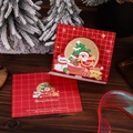 Detail of 3D Christmas card with red plaid design on dark wood table with festive ribbon - Santa Claus and Snowman