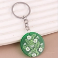 Nahaufnahme eines böhmischen Blumen-Acryl-Schlüsselanhängers mit silbernem Metallring - Grün