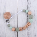 Detail of baby pacifier clip with green silicone beads, beech wood, and woven textures - Sage Green
