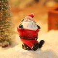Miniature resin Santa Claus figurine with a green gift bag for Christmas decor - Santa Claus with Backpack