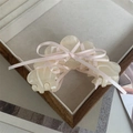 Close-up of a cream acetate hair claw clip with a delicate pink ribbon bow on a tray - Beige / Approx 8.5x4.5cm
