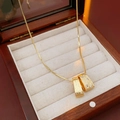 Primer plano del colgante dorado con textura y circonitas en joyero de madera - Colgante Cepillado Irregular / Dorado